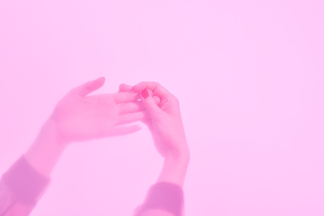 Das Bild zeigt zwei Hände die vom linken unteren Bildrand in das Bild hineinragen. Die eine Hand, mit geöffneter flacher Handfläche, wird von der anderen Hand sanft an den Fingerspitzen berührt. Der Bildhintergrund, wie auch die beiden Hände sind in hellem, transparentem Rosa gehalten.   The image shows two hands reaching into the picture from the lower left edge of the image. One hand, with open flat palm, is gently touched by the other hand at the fingertips. The background of the picture, as well as the two hands are kept in light, transparent pink.